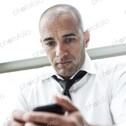 A middle eastern businessman texting on his cell phone.