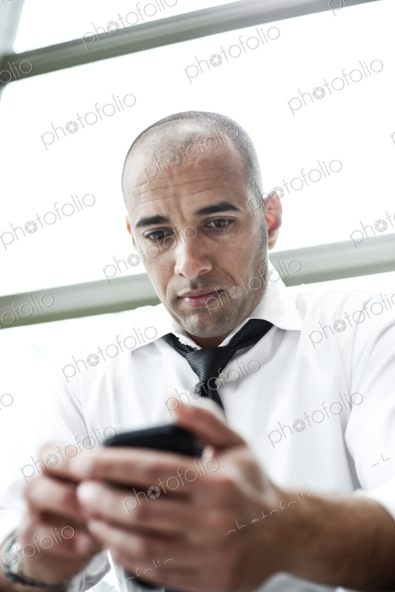 A middle eastern businessman texting on his cell phone.