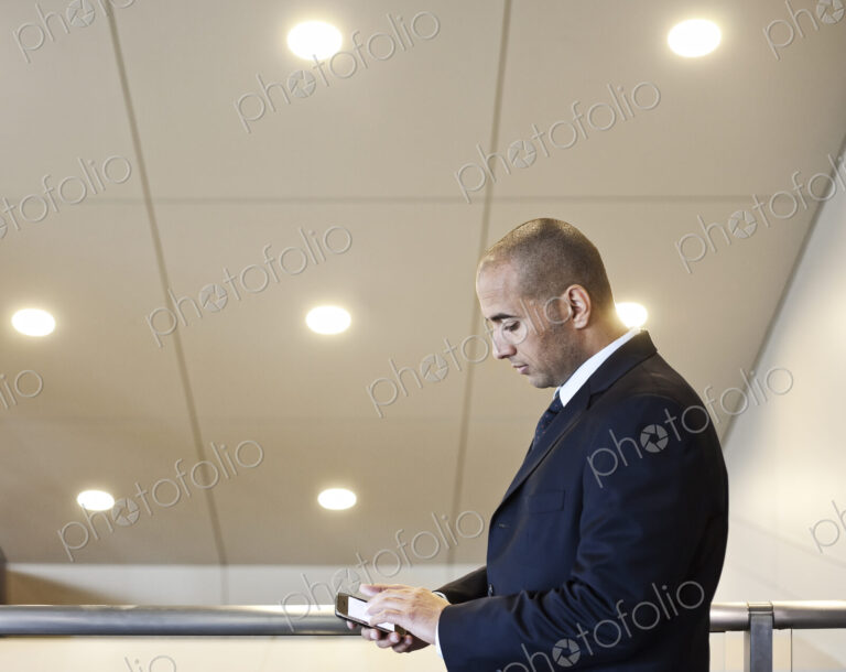 A middle eastern businessman working on a notebook computer standing in an office lobby.