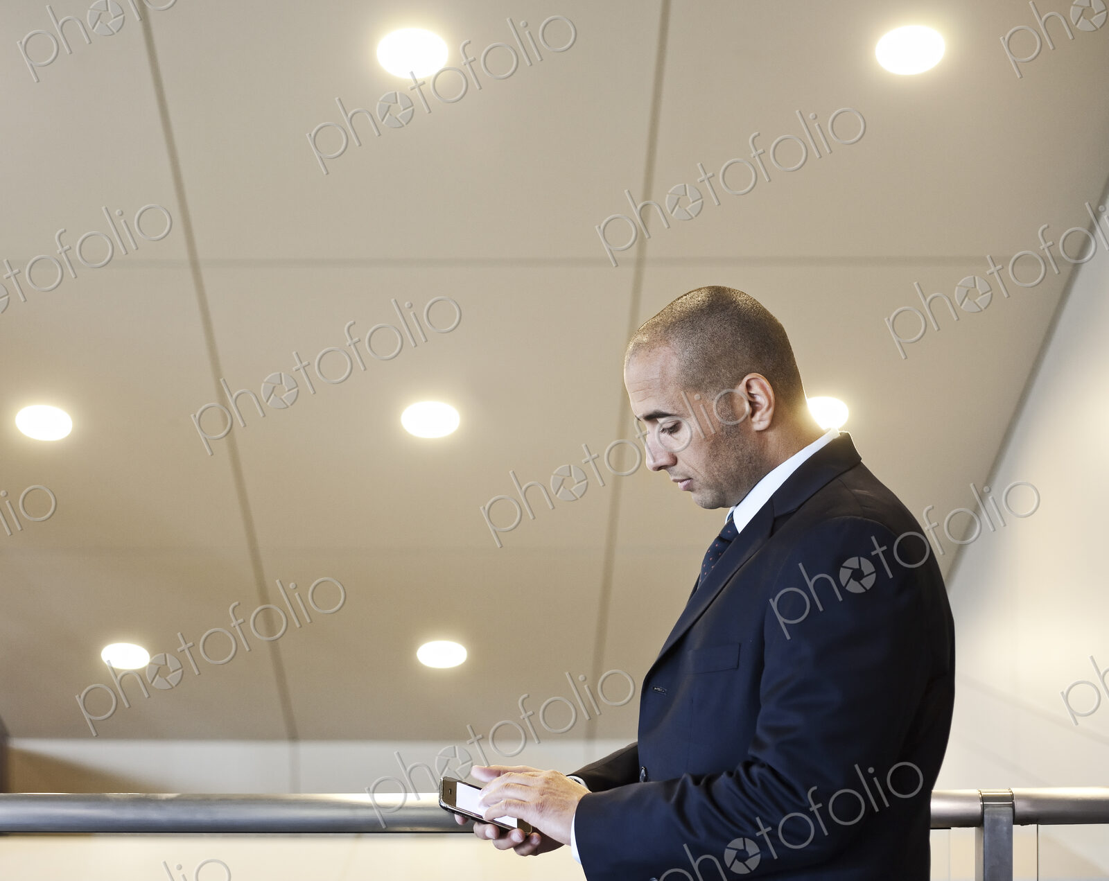 A middle eastern businessman working on a notebook computer standing in an office lobby.