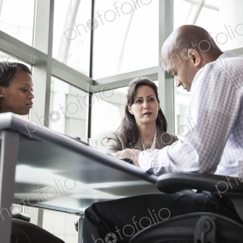 A mixed race group of male and female business people in a meeting at a conference…