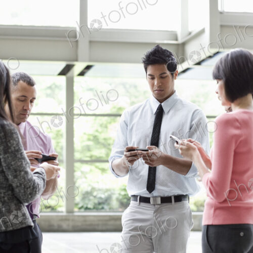 A mixed race group of male and female business people standing in the lobby area of a… A mixed race group of male and female business people standing in the lobby area of a…