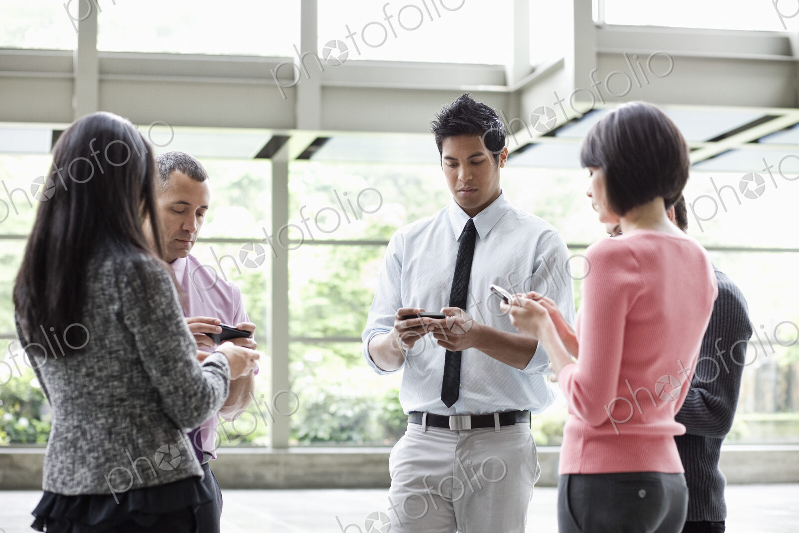 A mixed race group of male and female business people standing in the lobby area of a…