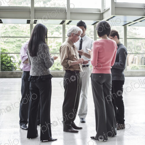 A mixed race group of male and female business people standing in the lobby area of a… A mixed race group of male and female business people standing in the lobby area of a…