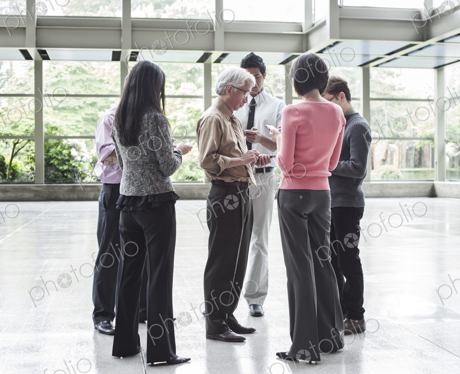 A mixed race group of male and female business people standing in the lobby area of a…