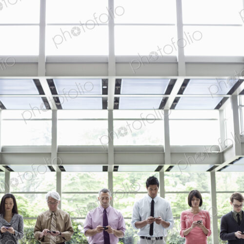 A mixed race group of male and female business people standing in the lobby area of a… A mixed race group of male and female business people standing in the lobby area of a…