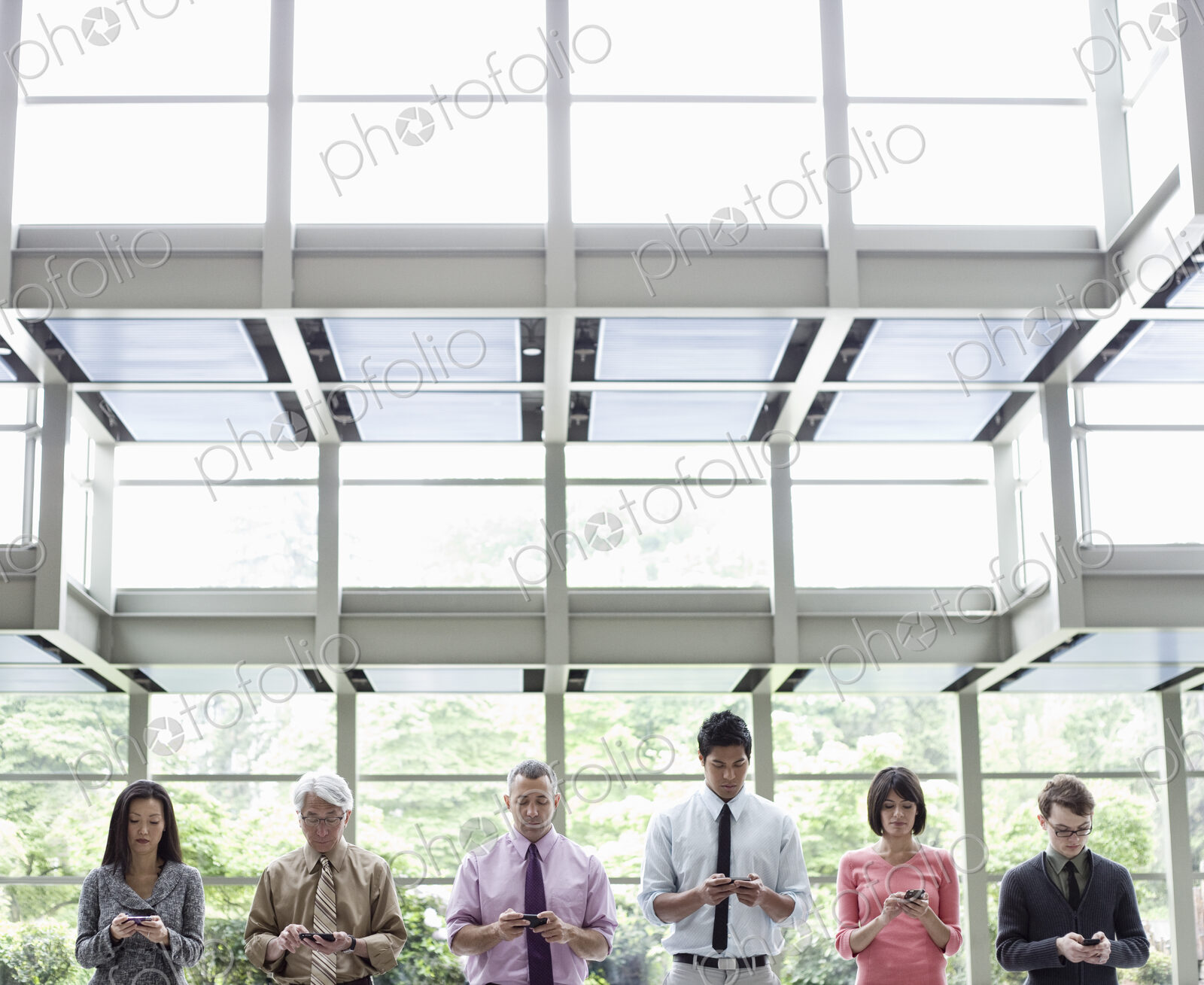 A mixed race group of male and female business people standing in the lobby area of a…