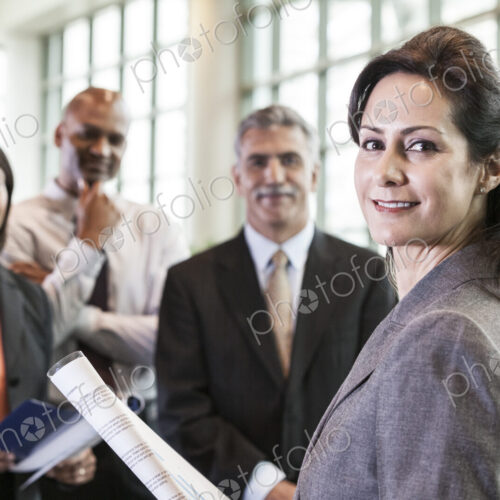 A mixed race group portrait of business people standing in a convention center lobby,… A mixed race group portrait of business people standing in a convention center lobby,…