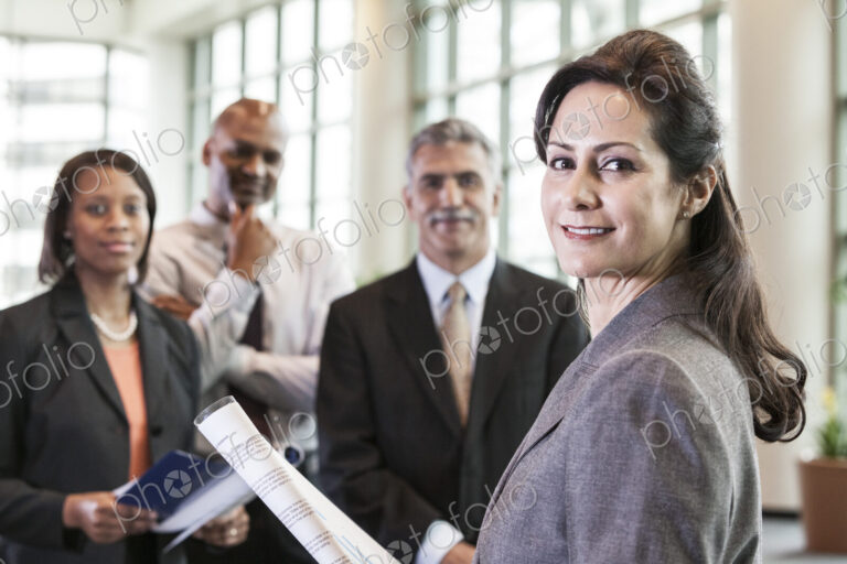 A mixed race group portrait of business people standing in a convention center lobby,…