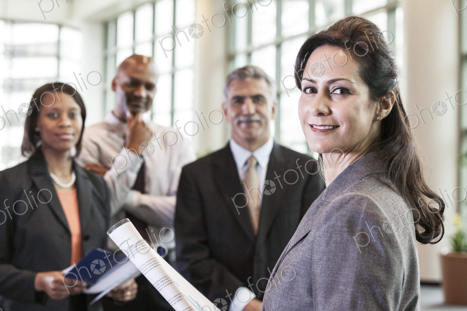A mixed race group portrait of business people standing in a convention center lobby,…