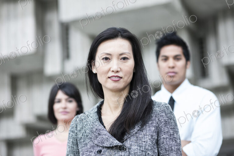 A mixed race team of business people with an Asian businesswoman in the lead.