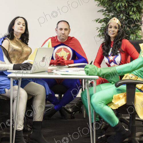 A mixed race team of office super heros sitting at a table in a planning meeting. A mixed race team of office super heros sitting at a table in a planning meeting.