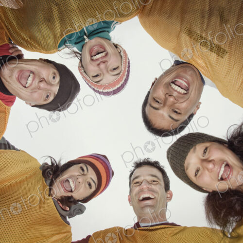 A mixed team of men and women in a huddle for a winter football game. View from below. A mixed team of men and women in a huddle for a winter football game. View from below.