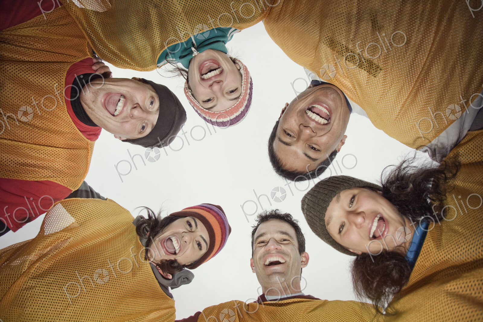 A mixed team of men and women in a huddle for a winter football game. View from below.