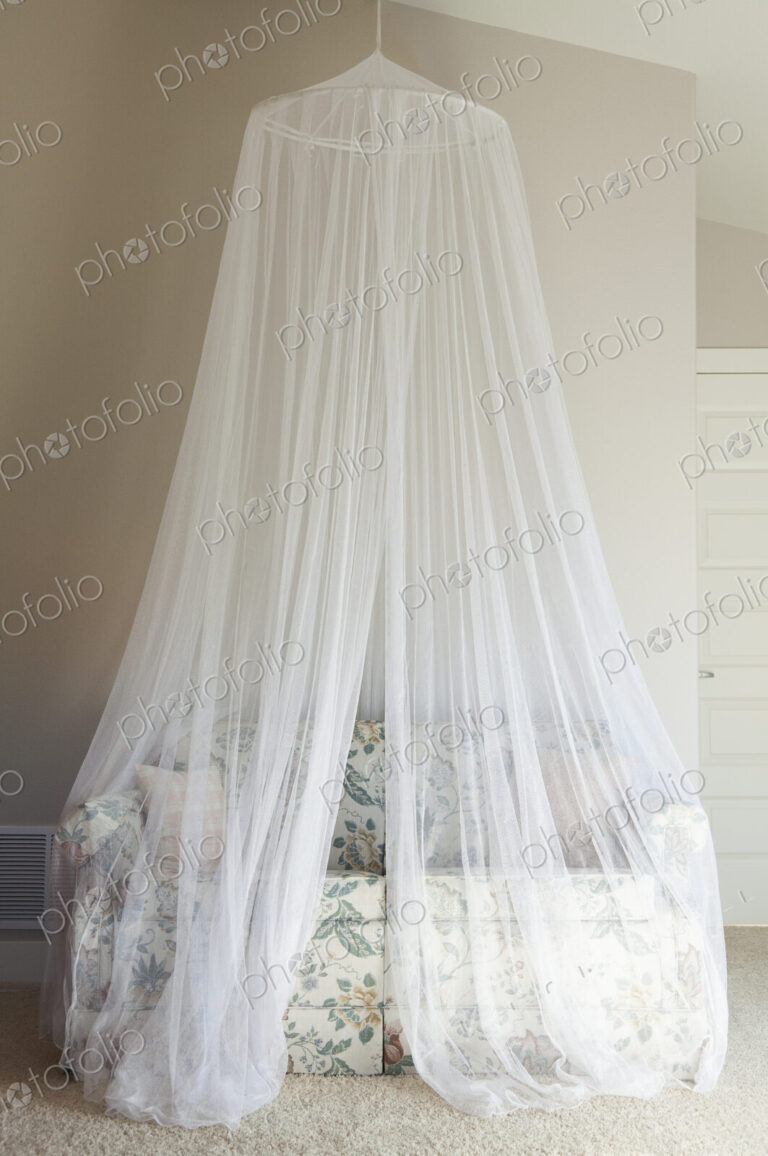 A mosquito net draped over a sofa.
