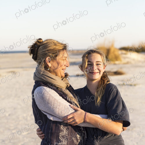 A mother and daughter embracing on a beach A mother and daughter embracing on a beach