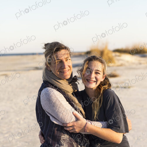 A mother and daughter embracing on a beach A mother and daughter embracing on a beach