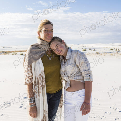 A mother and her teenage daughter side by side, arms around waists, in an open space A mother and her teenage daughter side by side, arms around waists, in an open space
