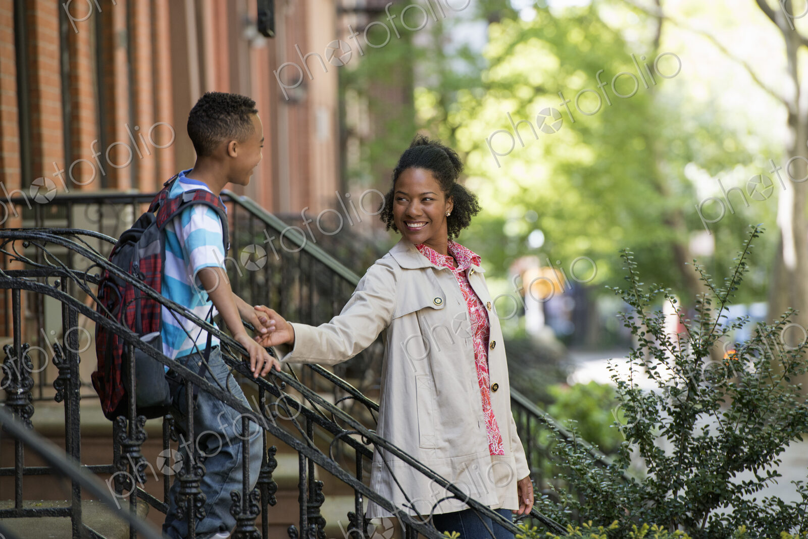 A mother and son, a woman and a boy on a flight of steps outside a brownstone building.