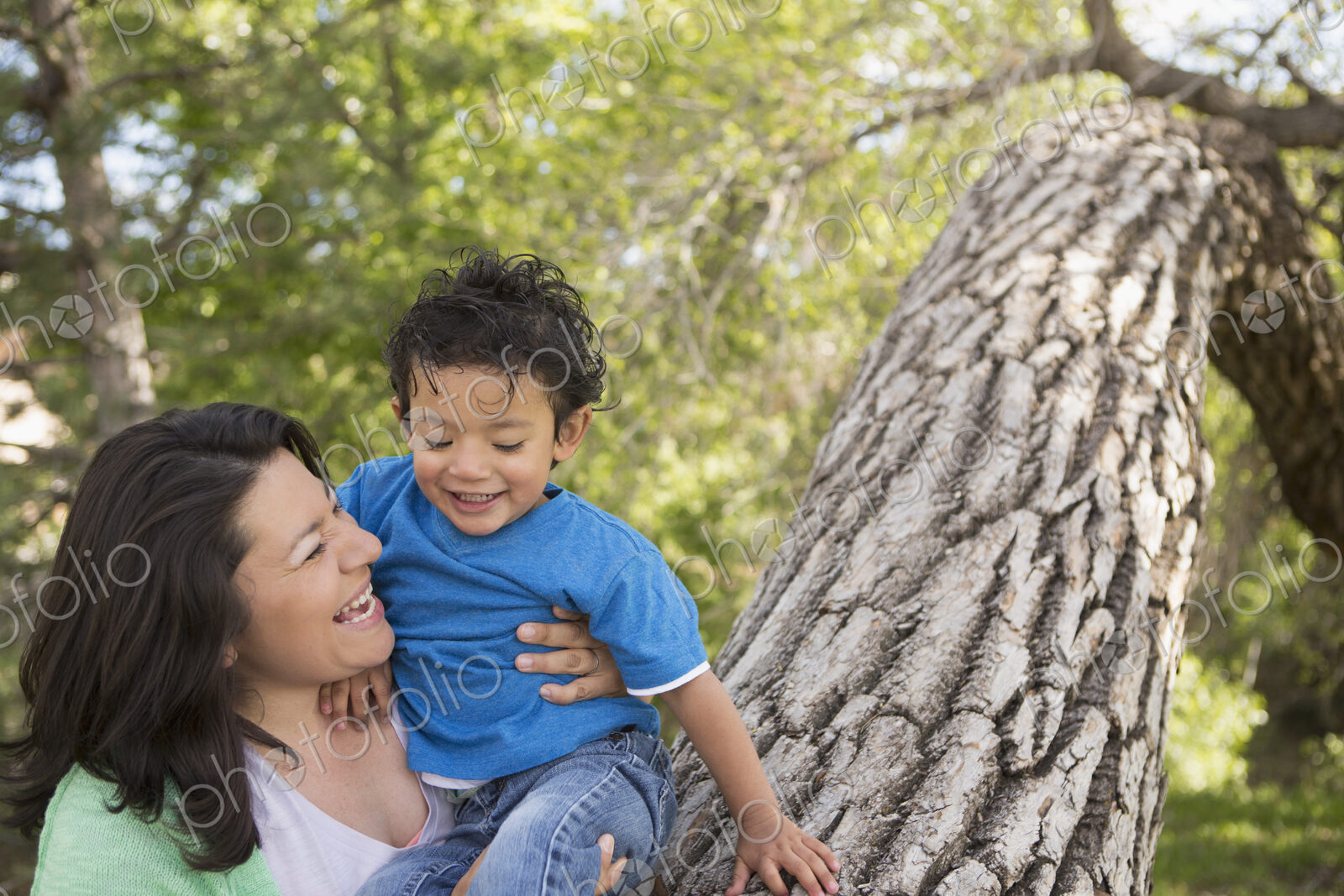 A mother and son in the park in Santa Fe, by a tall tree.