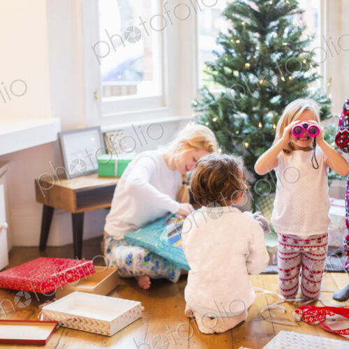 A mother and three children on Christmas morning opening presents.