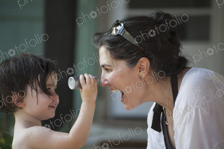 A mother and young daughter face to face, playing and laughing.