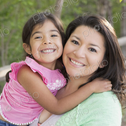 A mother in the park with her daughter, laughing and kissing each other.