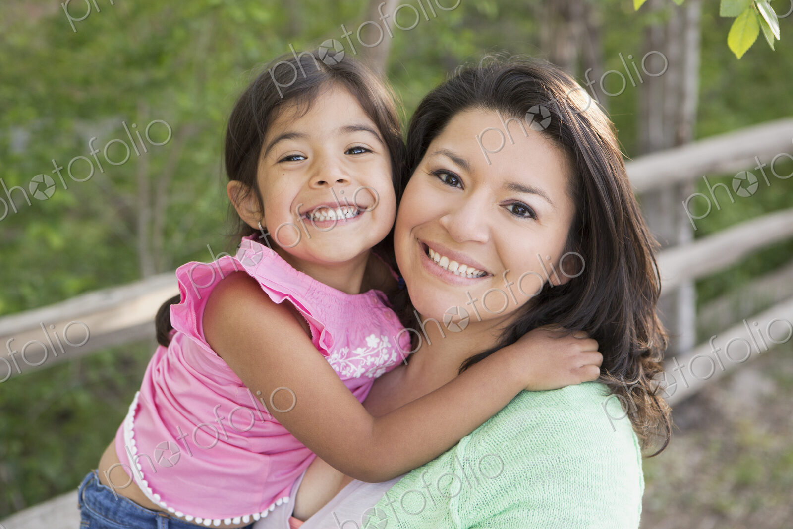 A mother in the park with her daughter, laughing and kissing each other.