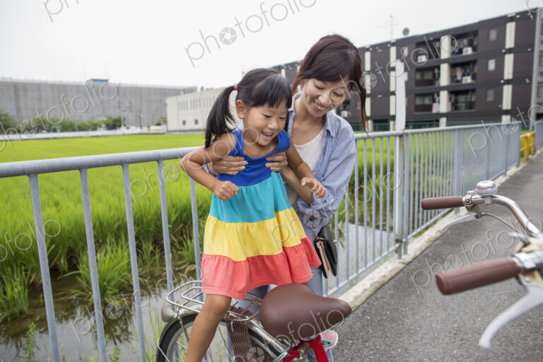 A mother lifting her daughter onto a bicycle.