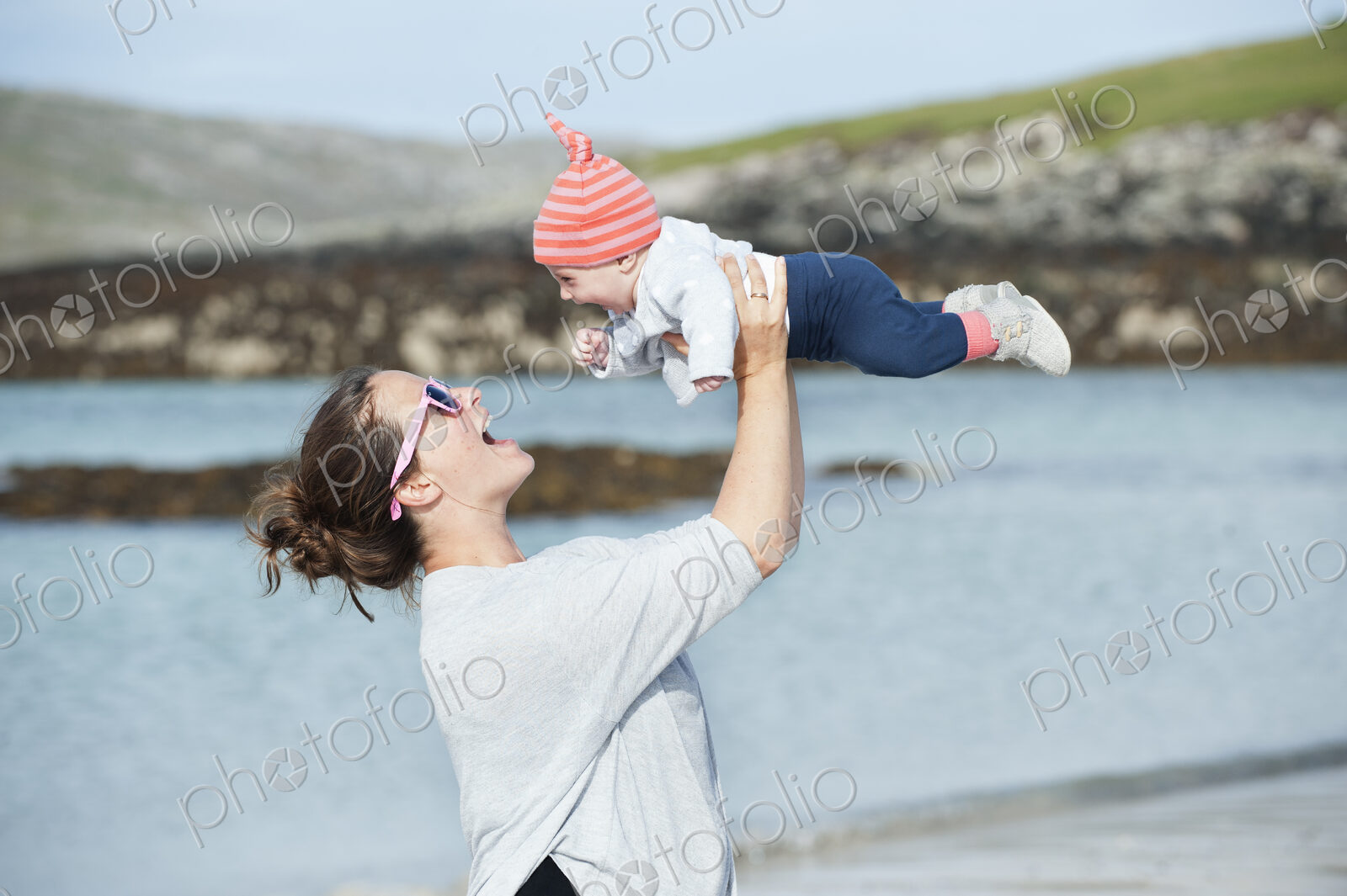 A mother raising her baby in the air. At the seaside.