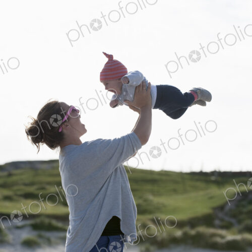 A mother raising her baby in the air. At the seaside. A mother raising her baby in the air. At the seaside.