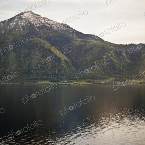 A mountain peak towering over a lake, creating a reflection on the calm water surface. A mountain peak towering over a lake, creating a reflection on the calm water surface.