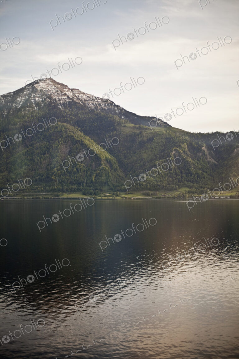 A mountain peak towering over a lake, creating a reflection on the calm water surface.