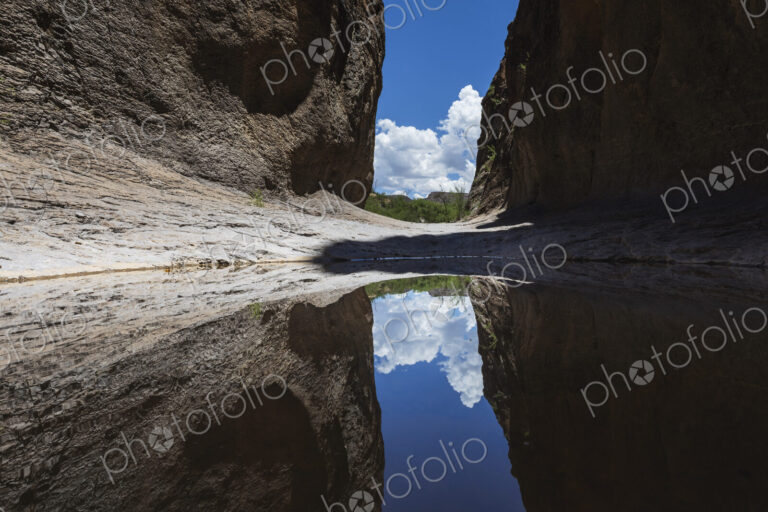A narrow slot canyon with a mirror reflection in the water near Lajitas.