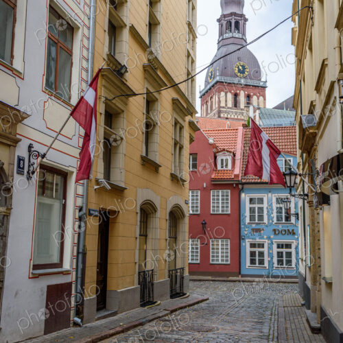 A narrow street with historic buildings in Riga, painted different colours and a bell…
