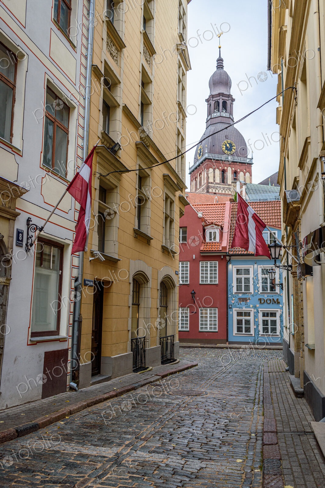 A narrow street with historic buildings in Riga, painted different colours and a bell…