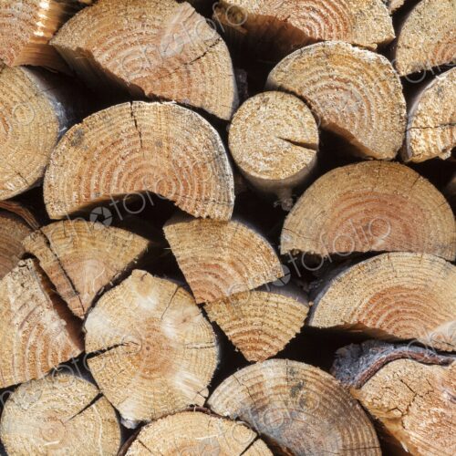 A neatly stacked pile of cut firewood showcases the natural texture and pattern of…