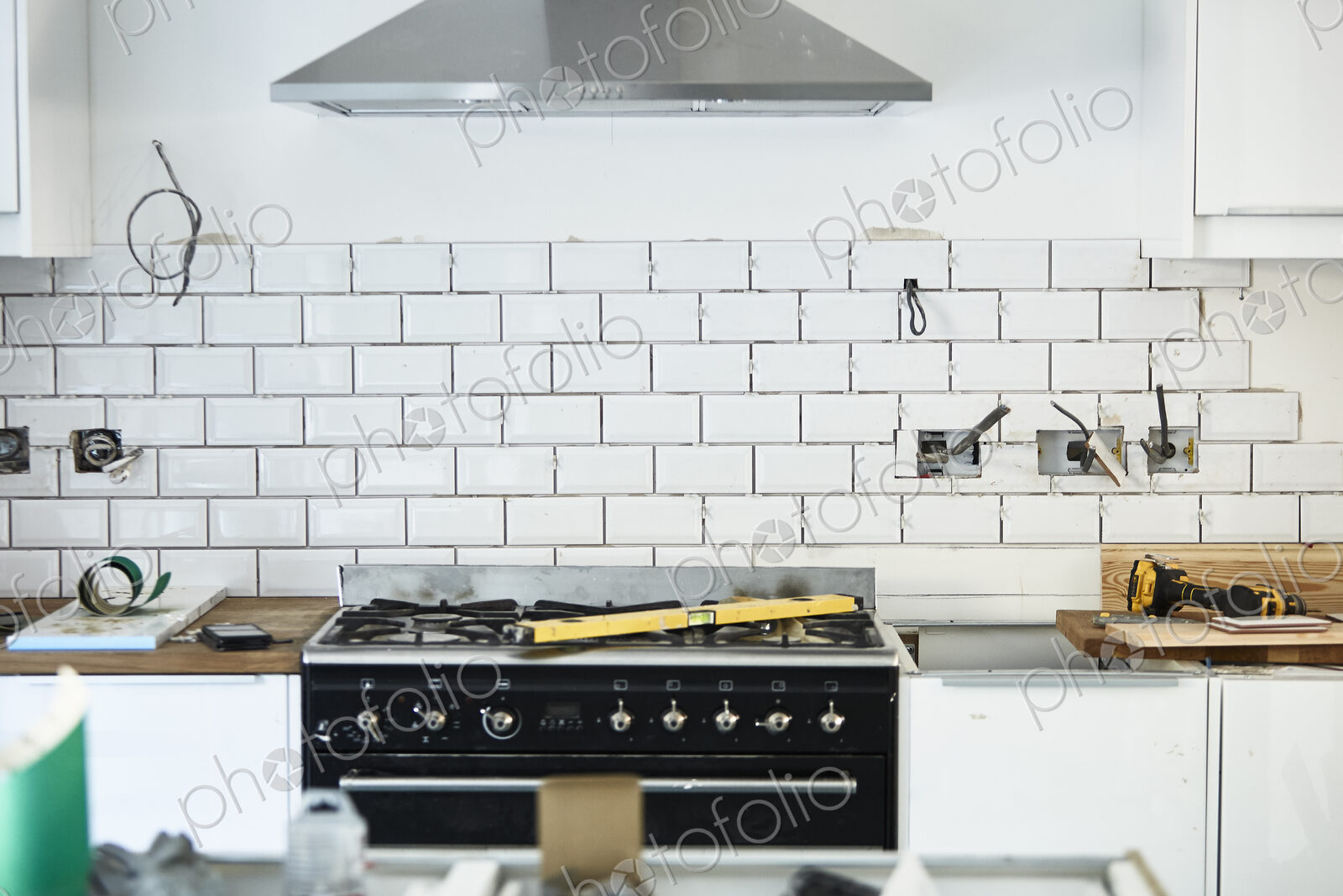 A newly installed kitchen, new cupboards and range, and tiling on the walls.