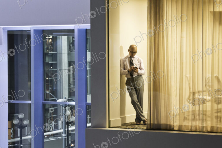 A night view looking into a conference room with an asisan businessman working on his…