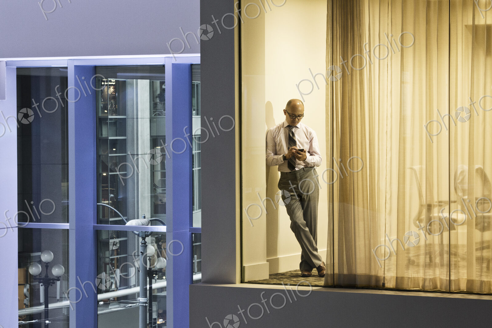 A night view looking into a conference room with an asisan businessman working on his…