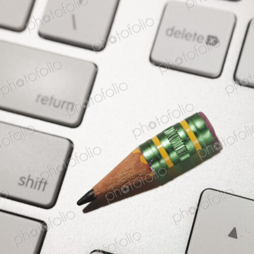 A nub of a lead pencil on a computer keyboard, vintage writing method and modern tools