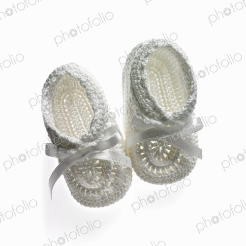 A pair of white baby booties, shoes for infants.