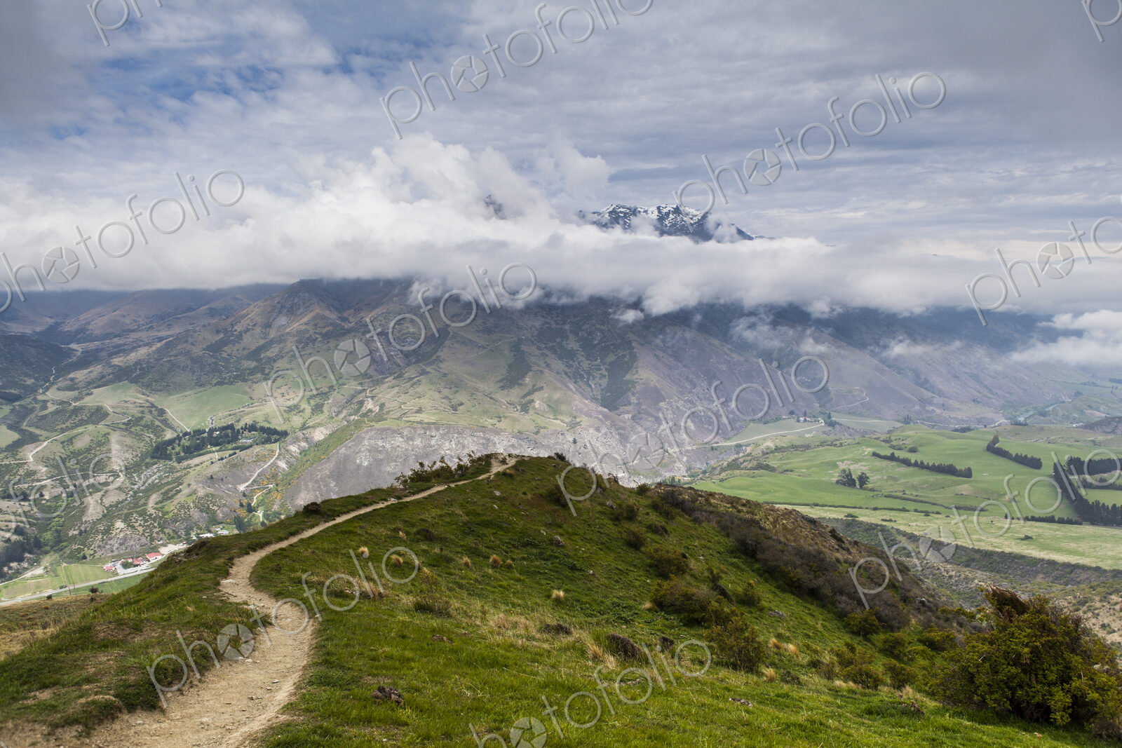A panoramic view across a valley to snow covered mountains.