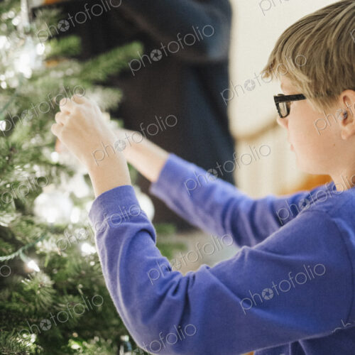 A person decorating a Christmas tree at home. A person decorating a Christmas tree at home.