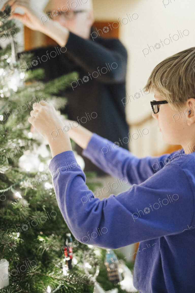 A person decorating a Christmas tree at home.