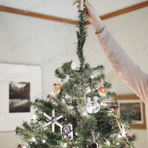 A person decorating a Christmas tree at home. A person decorating a Christmas tree at home.