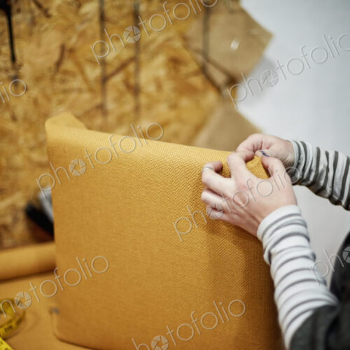 A person fitting a yellow fabric cover to a chair back.
