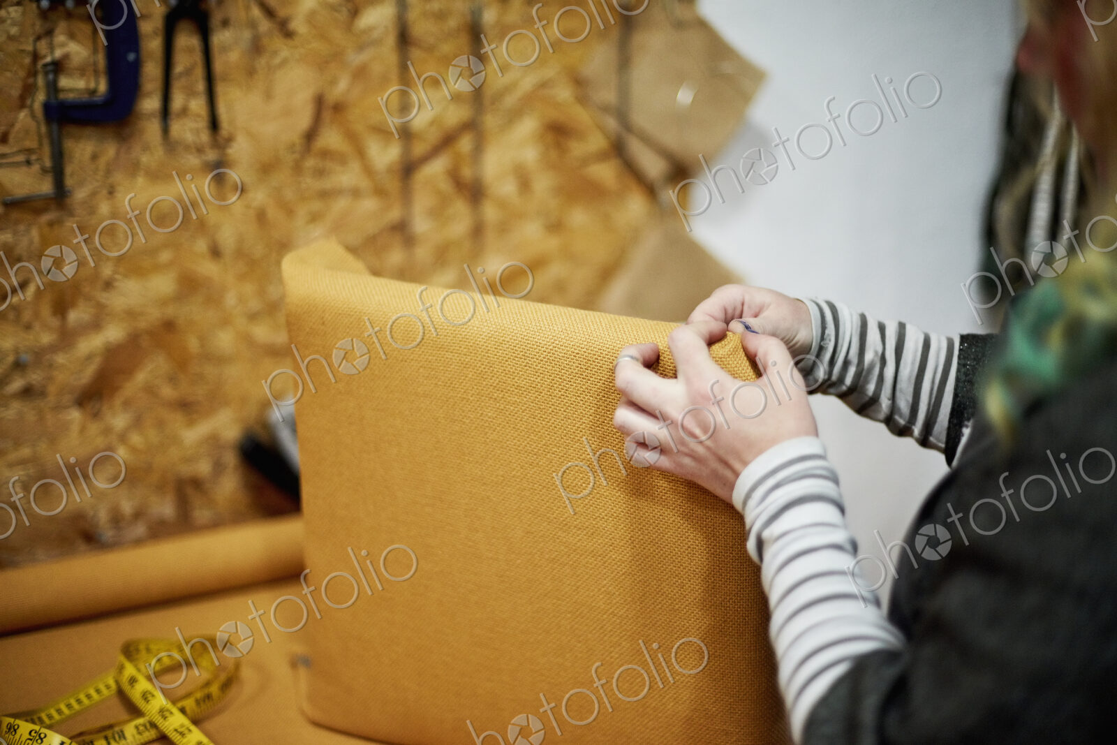 A person fitting a yellow fabric cover to a chair back.