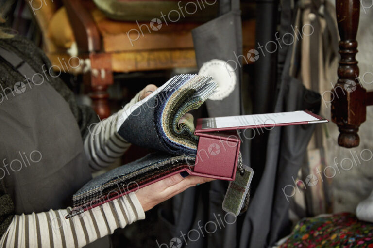 A person flicking through a fabric sample book, looking at colours and patterns.