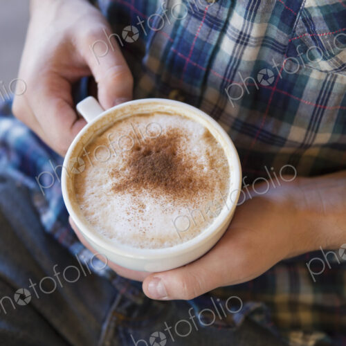 A person holding a cup of coffee in two hands. A person holding a cup of coffee in two hands.